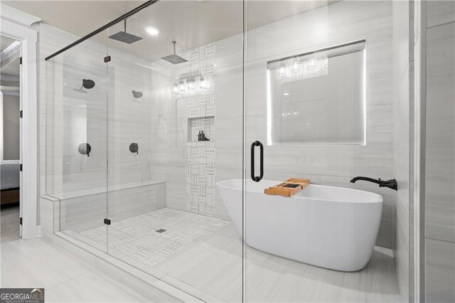 bathroom featuring a stall shower, a freestanding bath, and tile walls