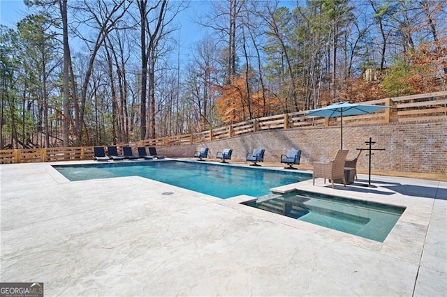 view of swimming pool featuring a patio area, a fenced backyard, and a pool with connected hot tub