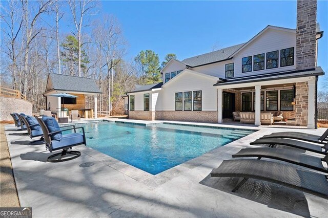 view of swimming pool with a fenced in pool, an outbuilding, a patio area, and outdoor lounge area