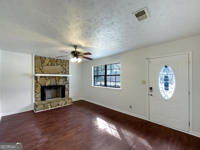 entrance foyer with visible vents, a ceiling fan, wood finished floors, a textured ceiling, and a stone fireplace