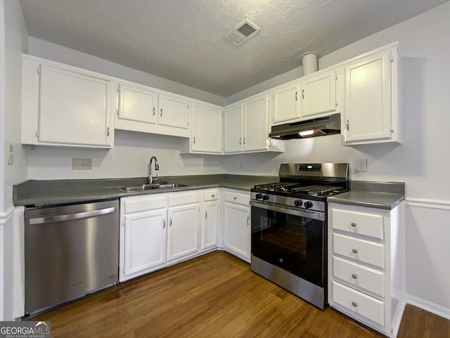 kitchen with visible vents, dark countertops, stainless steel appliances, under cabinet range hood, and a sink