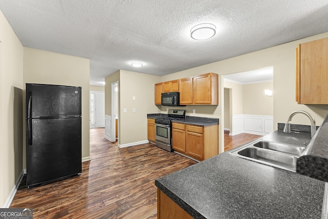 kitchen featuring dark countertops, black appliances, dark wood-style flooring, and a sink