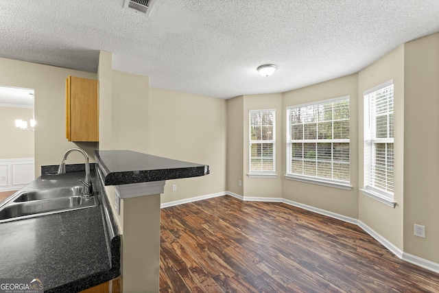 kitchen with baseboards, visible vents, dark countertops, dark wood-style flooring, and a sink