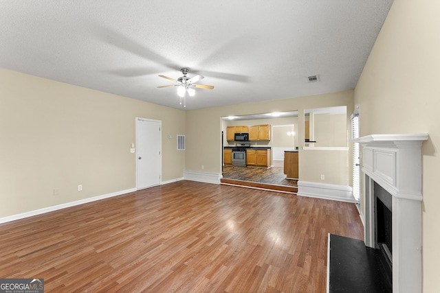 unfurnished living room with baseboards, a fireplace with flush hearth, visible vents, and light wood-style floors