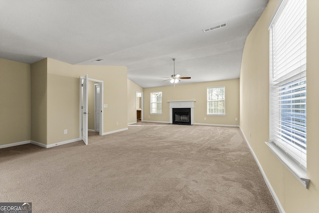 unfurnished living room featuring carpet, a fireplace, visible vents, a ceiling fan, and baseboards