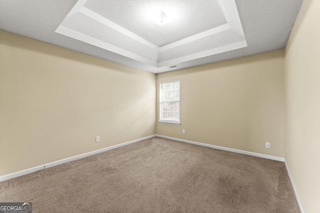 unfurnished room with a tray ceiling, carpet flooring, visible vents, and baseboards