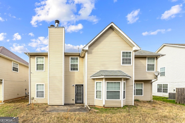 back of property featuring central AC unit and a chimney