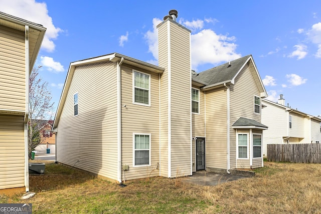 back of property with a chimney, fence, and a patio