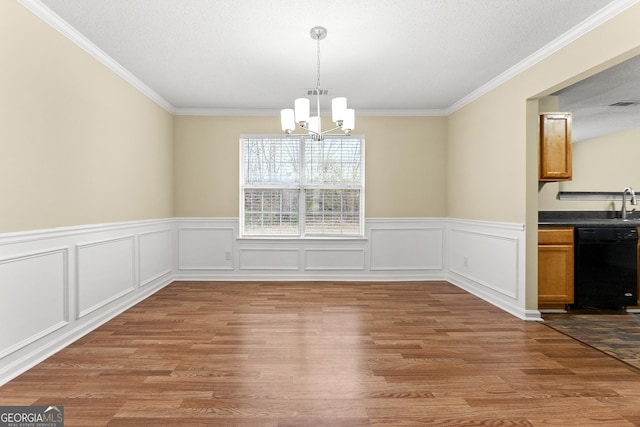 unfurnished dining area featuring an inviting chandelier, a textured ceiling, visible vents, and wood finished floors