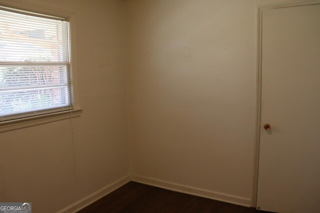 spare room with dark wood-style floors and baseboards