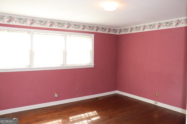 unfurnished room with dark wood finished floors and baseboards