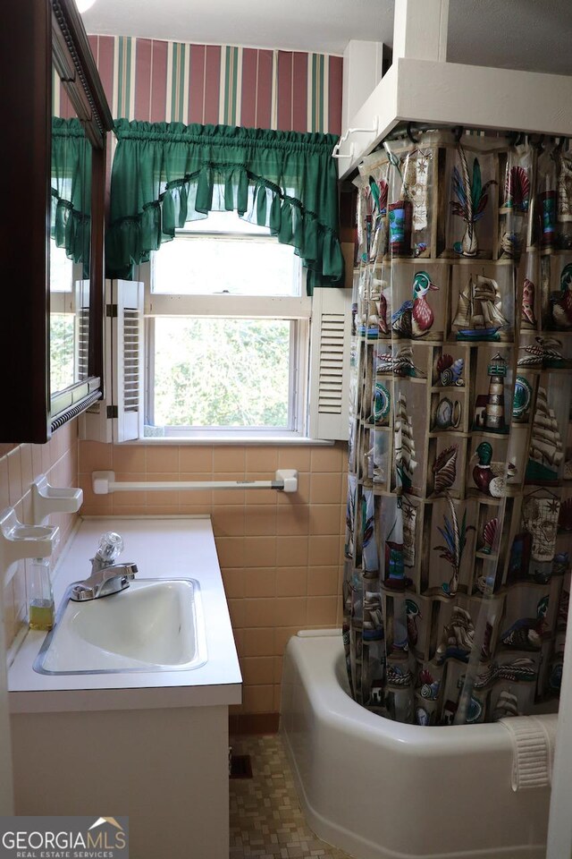 bathroom with shower / bath combination with curtain, vanity, and wallpapered walls