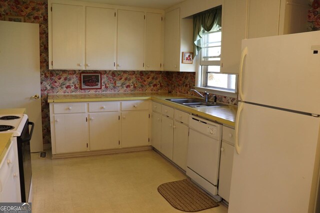 kitchen featuring light floors, light countertops, white cabinetry, a sink, and white appliances