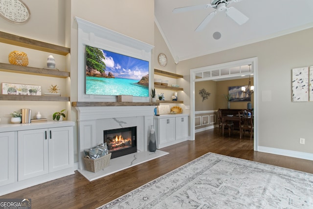 living area with lofted ceiling, dark wood finished floors, a ceiling fan, and a high end fireplace