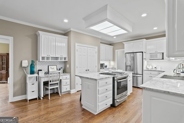 kitchen featuring stainless steel appliances, a sink, white cabinetry, and light stone countertops