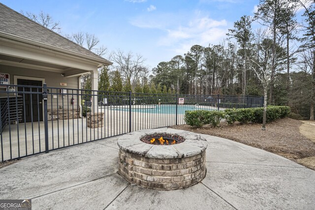 community pool with an outdoor fire pit, a patio area, and fence