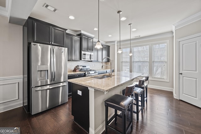 kitchen featuring a kitchen island with sink, stainless steel appliances, a sink, visible vents, and decorative light fixtures