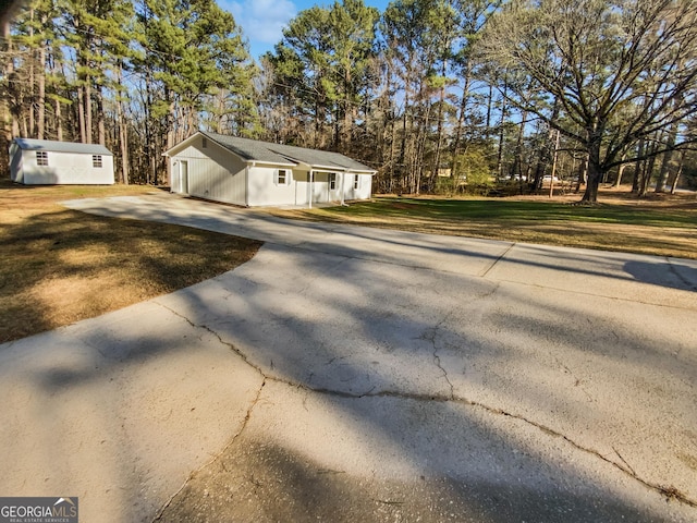 view of home's exterior featuring concrete driveway, a lawn, and an outdoor structure