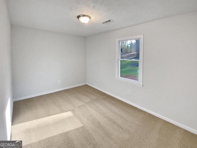 carpeted empty room with visible vents and baseboards