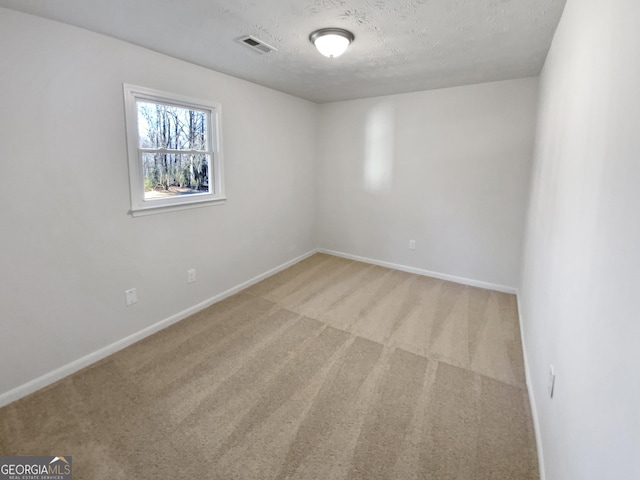 unfurnished room with baseboards, visible vents, light carpet, and a textured ceiling