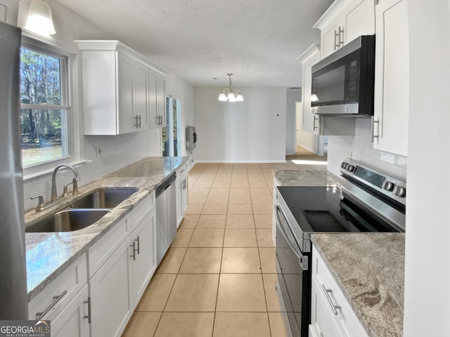 kitchen with light tile patterned floors, tasteful backsplash, appliances with stainless steel finishes, white cabinetry, and a sink