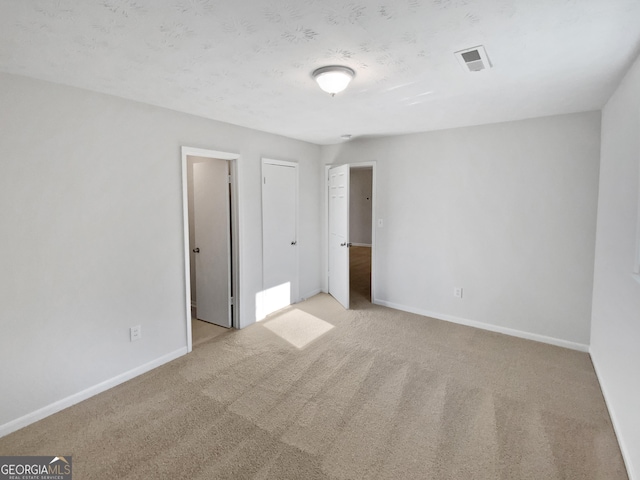 unfurnished bedroom featuring carpet, visible vents, and baseboards