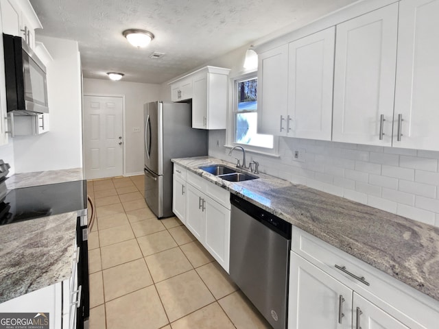 kitchen with white cabinets, stainless steel appliances, a sink, and light tile patterned flooring