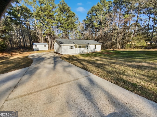 view of front of house featuring an outbuilding, concrete driveway, and a front lawn