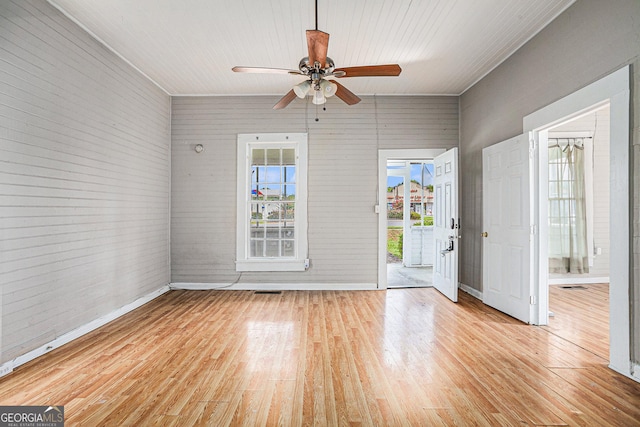 interior space featuring brick wall, light wood finished floors, a ceiling fan, and baseboards