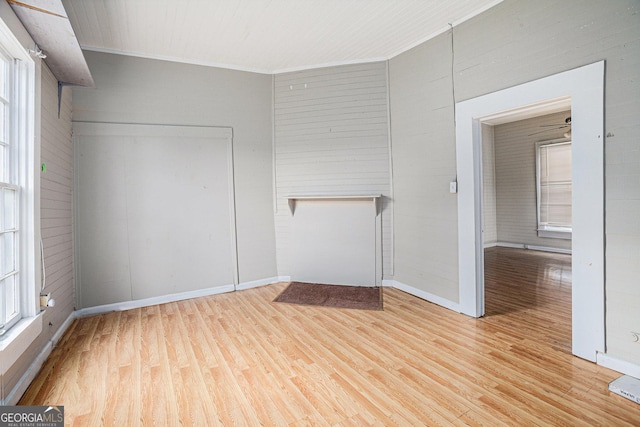 empty room featuring light wood finished floors, baseboards, and ornamental molding