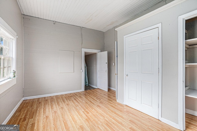 unfurnished bedroom with baseboards, wood ceiling, and light wood-style floors