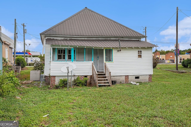 rear view of house featuring metal roof, crawl space, and a lawn