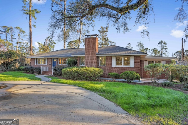 single story home featuring a front yard, a chimney, and brick siding