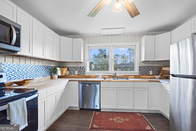 kitchen featuring appliances with stainless steel finishes, white cabinets, a sink, and decorative backsplash