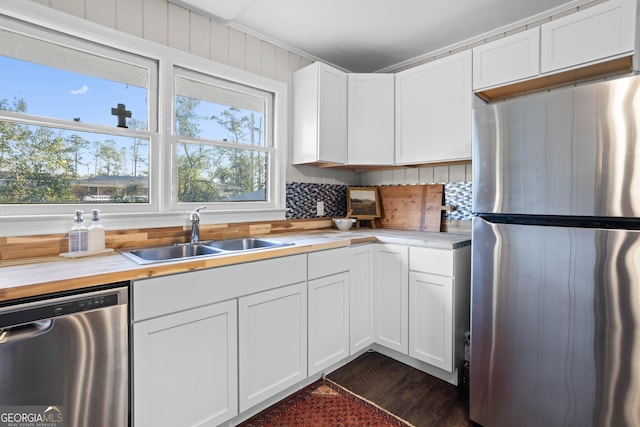 kitchen with backsplash, appliances with stainless steel finishes, white cabinets, and a sink