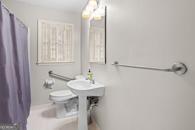 full bath featuring a shower with shower curtain, toilet, a sink, tile patterned flooring, and baseboards