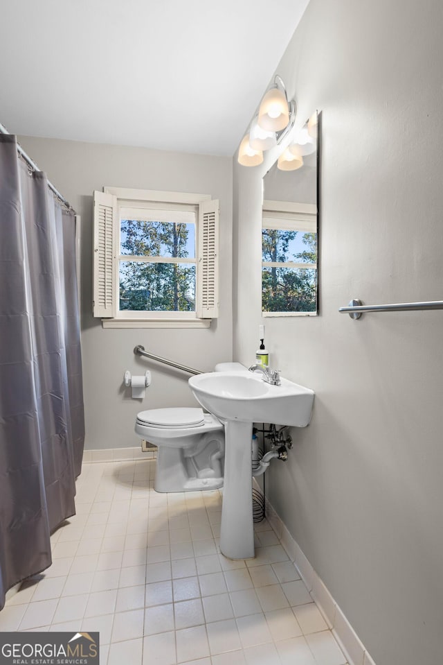 bathroom with toilet, baseboards, a wealth of natural light, and tile patterned floors