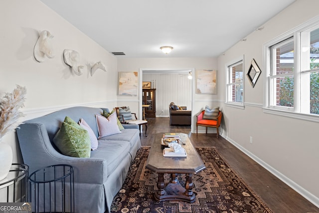 living room with dark wood-type flooring, visible vents, and baseboards