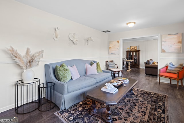 living room featuring dark wood-style flooring, visible vents, and baseboards