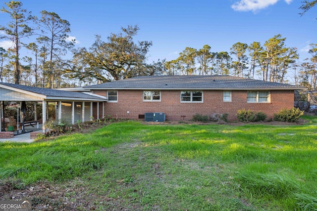 rear view of house with central AC unit, a patio area, brick siding, and a yard