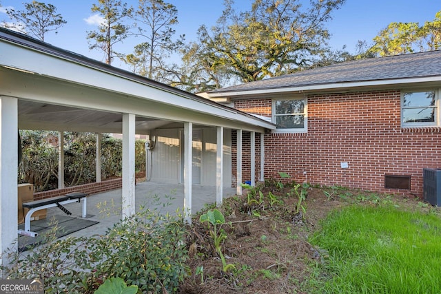 view of side of property featuring a patio and brick siding