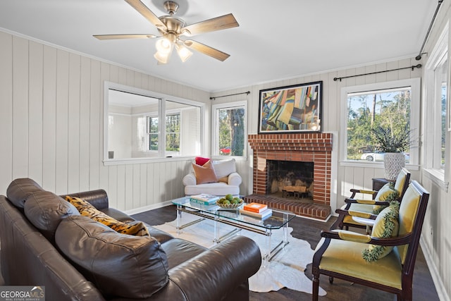 living room featuring dark wood-type flooring, a fireplace, plenty of natural light, and ornamental molding