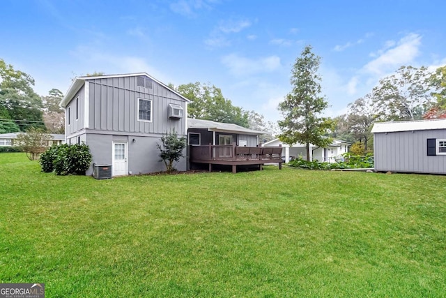 back of house with central AC unit, a deck, board and batten siding, and a yard