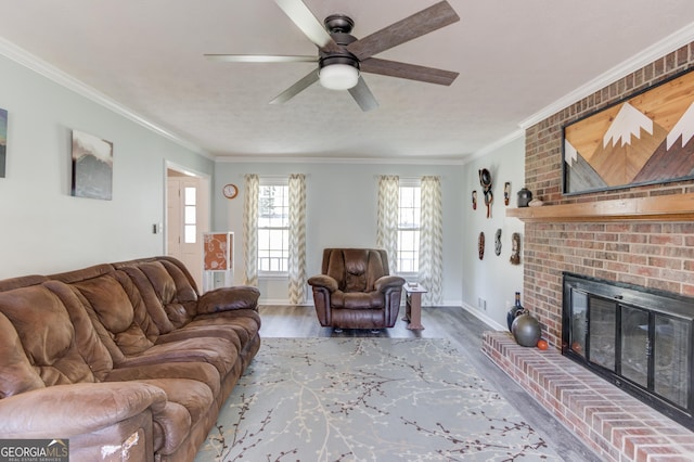 living area featuring ornamental molding, a brick fireplace, baseboards, and wood finished floors