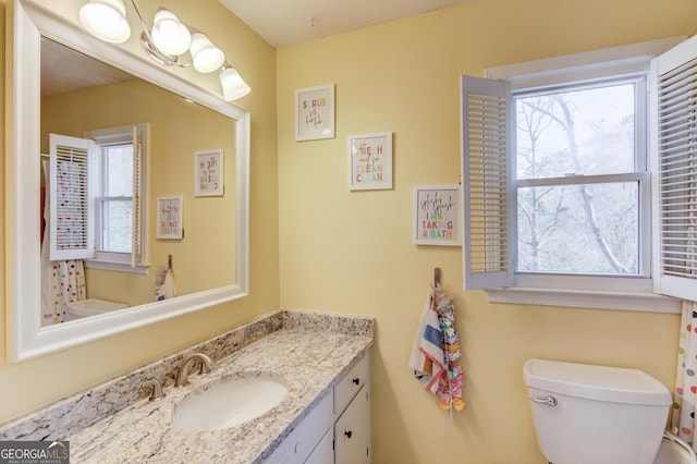 bathroom with toilet, vanity, and a healthy amount of sunlight