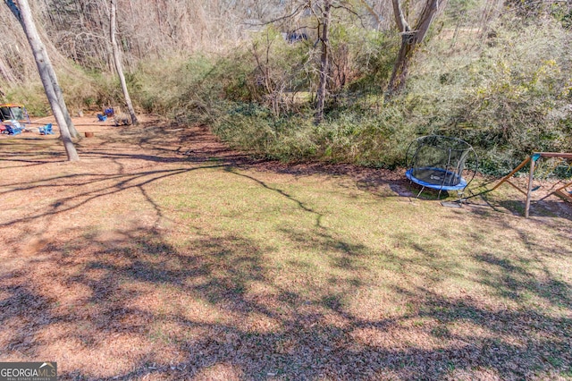 view of yard with a trampoline and playground community