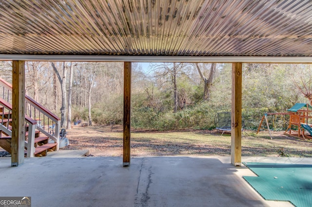 view of patio with stairs, a trampoline, a playground, and a wooded view