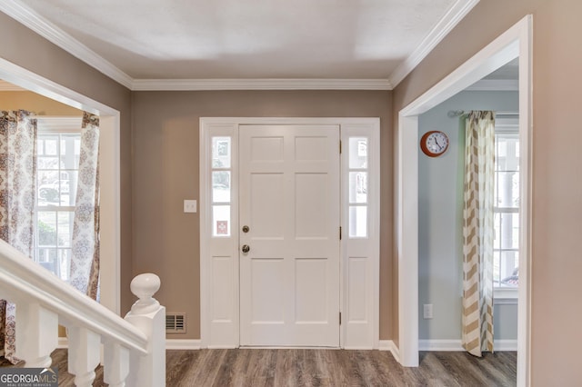 entryway with dark wood-style floors, crown molding, visible vents, and baseboards