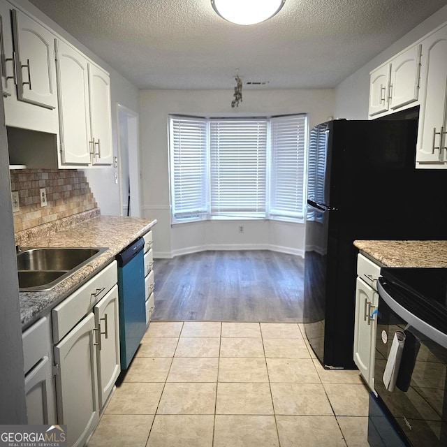 kitchen featuring dishwasher, black electric range, light tile patterned floors, and white cabinets