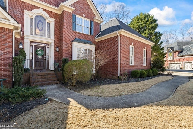 view of front of home featuring entry steps, roof with shingles, and brick siding